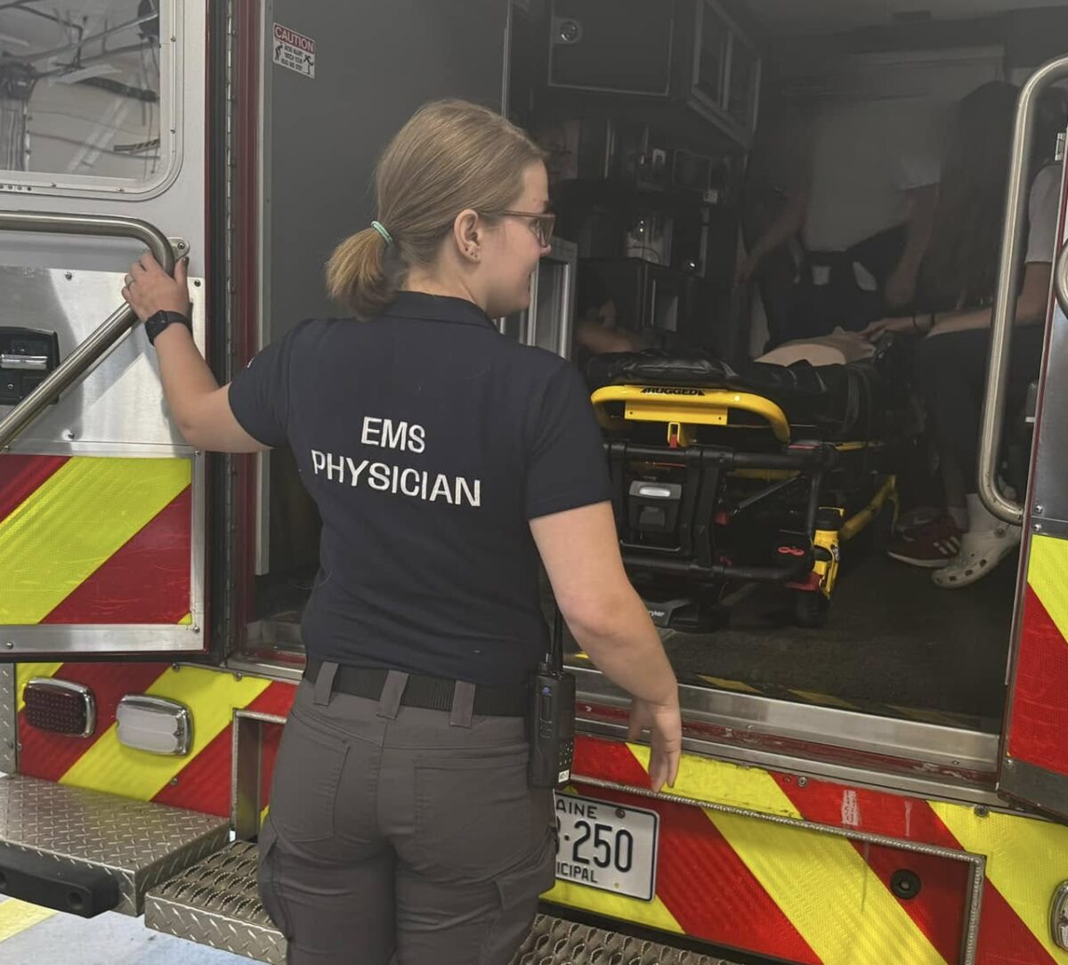 An MD3 EMS physician preparing equipment at the back of an ambulance
